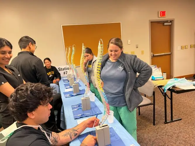 Group participates in a hands-on spine care workshop with models and medical supplies in a classroom.
