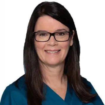 Smiling woman with long dark hair and glasses in a teal top, posed against a white background.